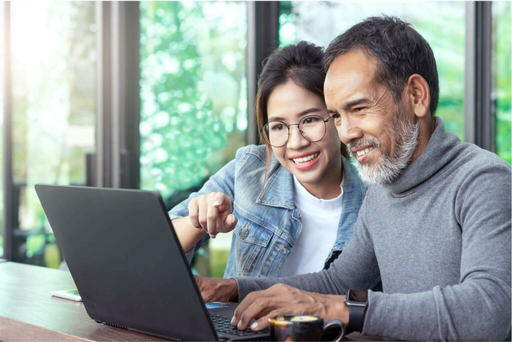 Father and daughter looking at a laptop together.