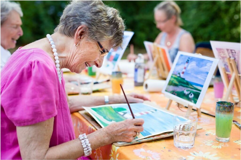 Group of older adults painting together outside.